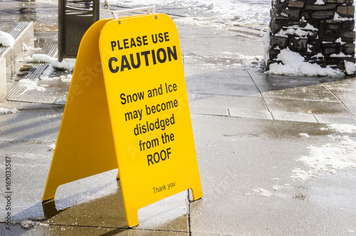 Sign on a Sidewalk Warning Pedestrian of the Possibility that the Snow May fall from the Roof photo