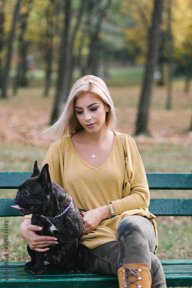 Beautiful and happy young blond woman enjoying in autumn park with her adorable French bulldog puppy. Beautiful and happy young blond woman enjoying in autumn park with her adorable French bulldog puppy.