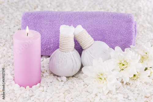 Spa. Still life. Candle of pink color, a towel and white flowers on a background of white pebbles