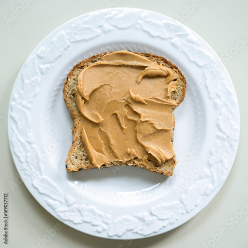 Konstfotografi Peanut butter slathered on a slice of multi grain bread.