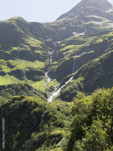 Mountain waterfall in Alps. Scenic Alpine rocky alpine mountines of Sportgastein in summer. Picturesque mountain cascade, great mountain massif, sunny weather. Sport hiking landscape background.