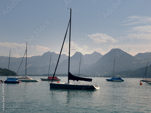 Small harbor in Wolfgang see mountain lake. Anchored yachts, sunny weather. Summer sailing in Alps. Sport hiking landscape background. © weenee