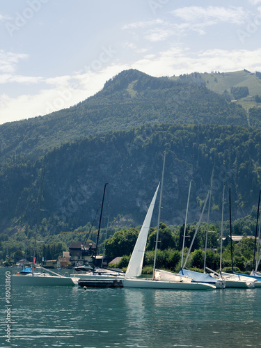 Small harbor in Wolfgang see mountain lake. Anchored yachts, sunny weather. Summer sailing in Alps. Sport hiking landscape background.