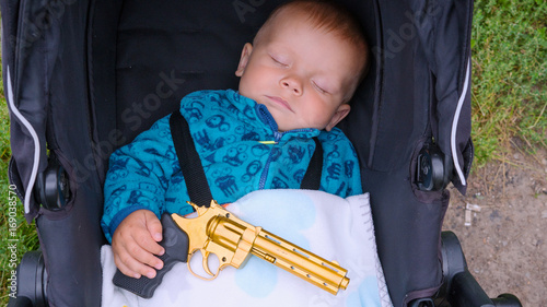 Sleeping baby with a gun in his hands