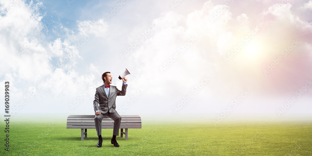 Businessman in summer park announcing something in loudspeaker