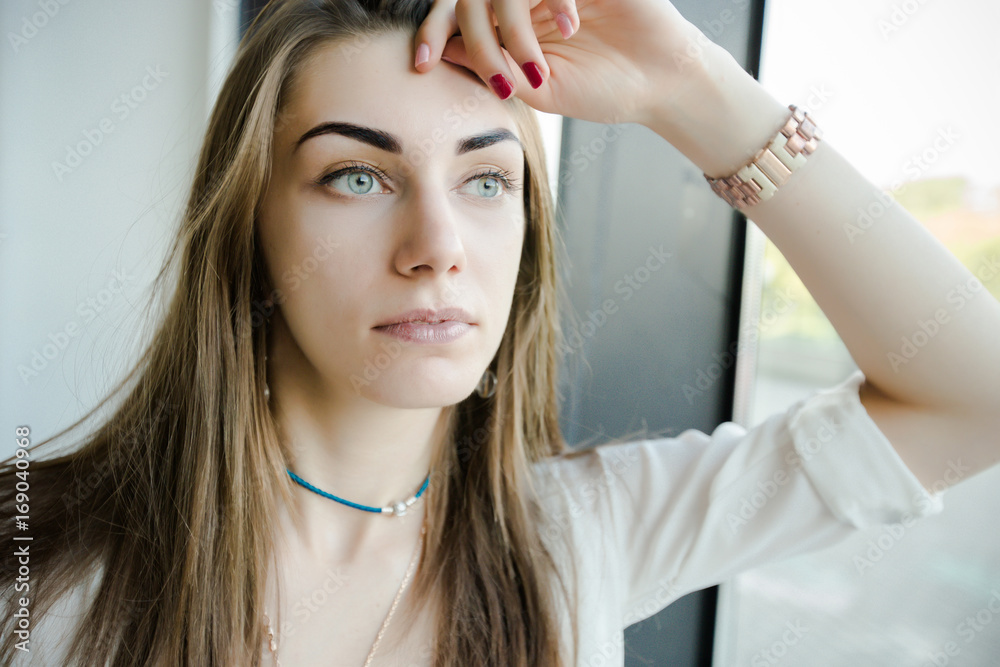 Portrait of trendy young caucasian woman posing near a window. Portrait of trendy young caucasian woman posing near a window.