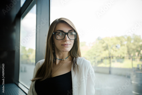 Portrait of trendy young caucasian woman posing near a window.