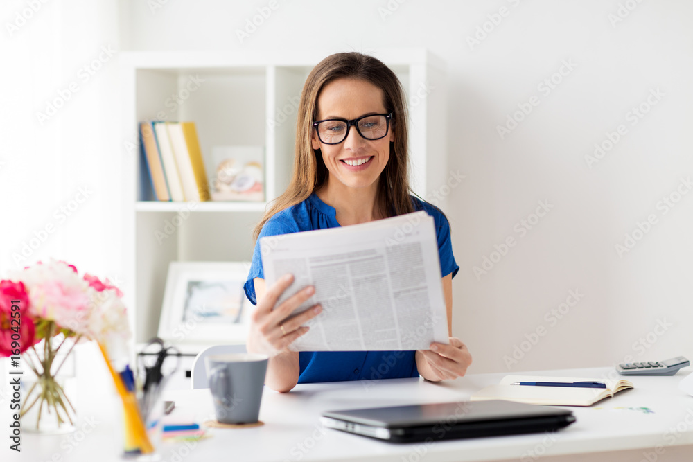 happy woman in glasses reading newspaper at office happy woman in glasses reading newspaper at office