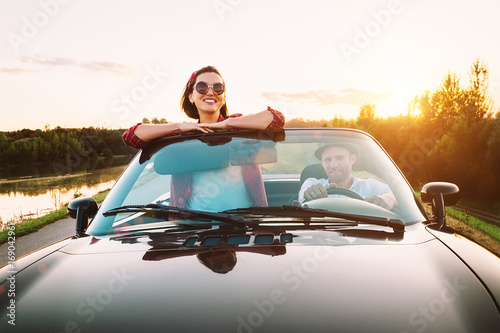 Traveling by car - couplr in love dgo by cabriolet car in sunset time photo
