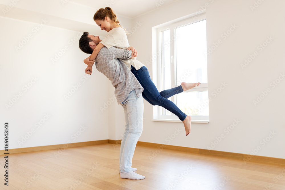 happy couple at empty room of new home