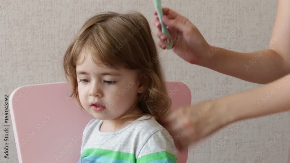 Woman brushing her daughter hair at home. Conceptual happy family Woman brushing her daughter hair at home. Conceptual happy family