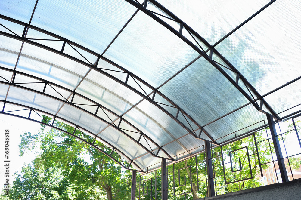 A canopy made of polycarbonate arc against the blue sky. Metal construction.
A canopy made of polycarbonate arc against the blue sky. Metal construction.