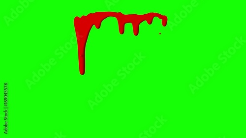 Red ink dripping over green screen background. Close-up shot