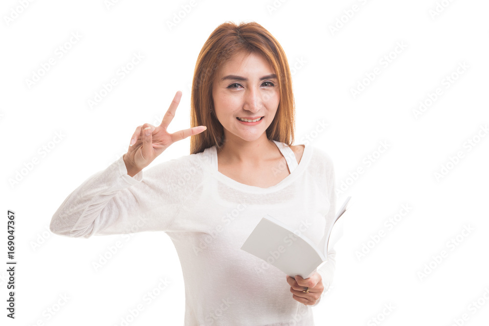 Young Asian woman show victor sign with a book. Young Asian woman show victor sign with a book.