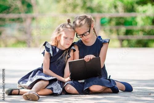 Adorable little school girls with notes and pencils outdoor. Back to school.