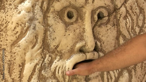 Mouth of truth, Rome, Italy, tourist putting his hand into the ancient mask. Man trying the famous legend to find out lies, Italian holidays and tourism destination