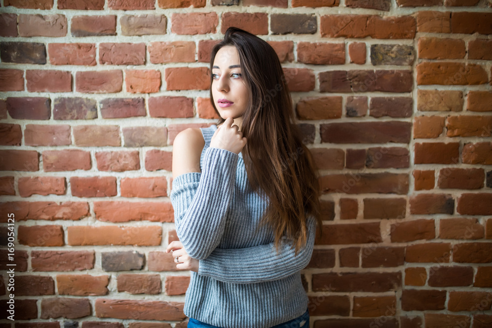 Pretty young Woman in casual against red brick wall