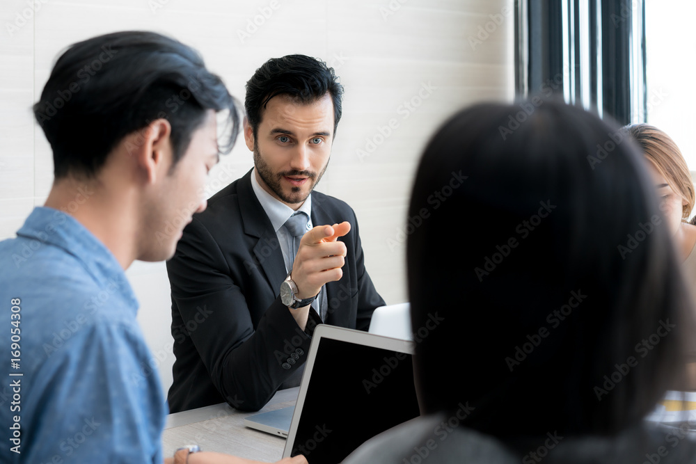 Fototapeta premium Young Businessman boss talking to employee, pointing to employee, businessman discussing with partner and have question to Subordinate in meeting.