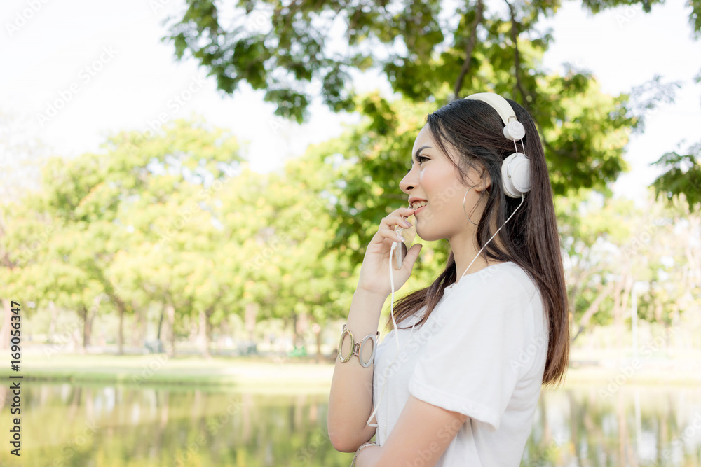 Beautiful young woman relaxing with smartphone and headphone listening to the music traveling Beautiful young woman relaxing with smartphone and headphone listening to the music traveling