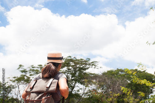 Woman traveler with backpack looking at wonderful forest