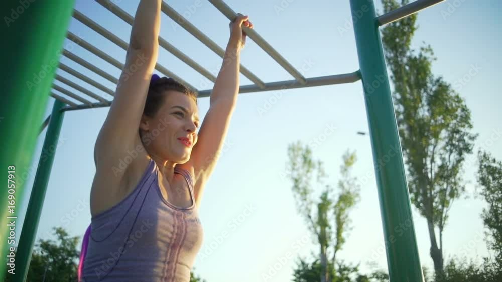 Beautiful young woman doing an exercise on the horizontal bar slow motion Beautiful young woman doing an exercise on the horizontal bar slow motion