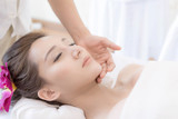 beautiful and healthy young woman relaxing with face massage  at beauty spa salon