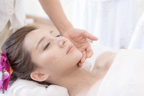 beautiful and healthy young woman relaxing with face massage at beauty spa salon