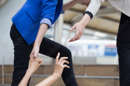 Business woman giving hand to bring her friend up