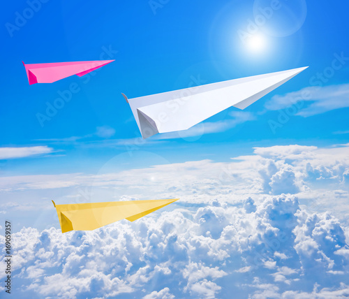 Paper plane flying against blue sky