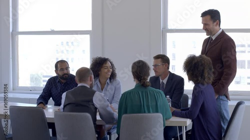 Mixed race team members in staff or board meeting, smile, laugh and nod in agreement during a meeting in a bright, day interior, urban office. 4K.