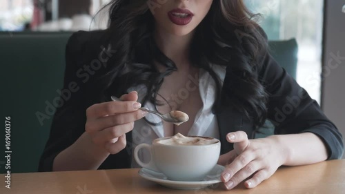 woman licking a coffee spoon with cup in her hand