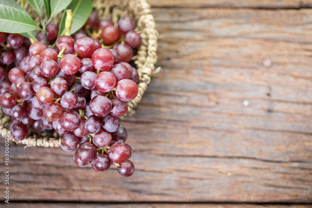 Red grapes in basket on old wooden table background Red grapes in basket on old wooden table background