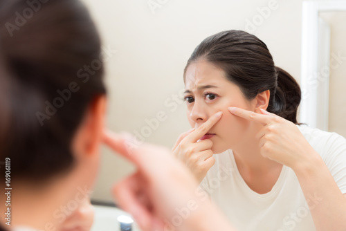 young sweet woman looking at bathroom mirror