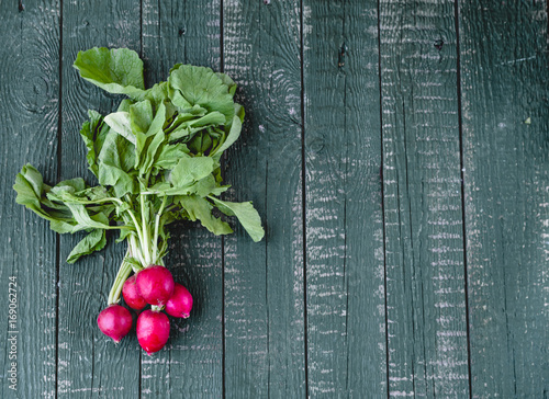 fresh radish on a green wooden background, top view, copy space
