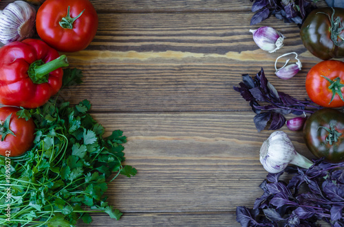 assorted tomatoes, paprika, garlic and herbs on a brown wooden table, top view, copy space