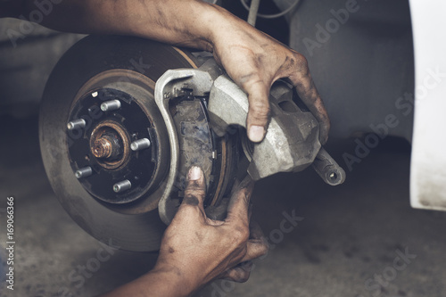Hands of mechanic changing car braker in auto repair service.