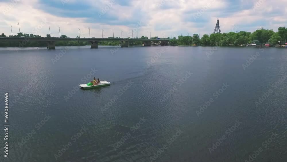Flying over girls floating pedal boat on lake water HD aerial panoramic video. Women relaxation on river at summer vacation. Recreation leisure nature background Flying over girls floating pedal boat on lake water HD aerial panoramic video. Women relaxation on river at summer vacation. Recreation leisure nature background