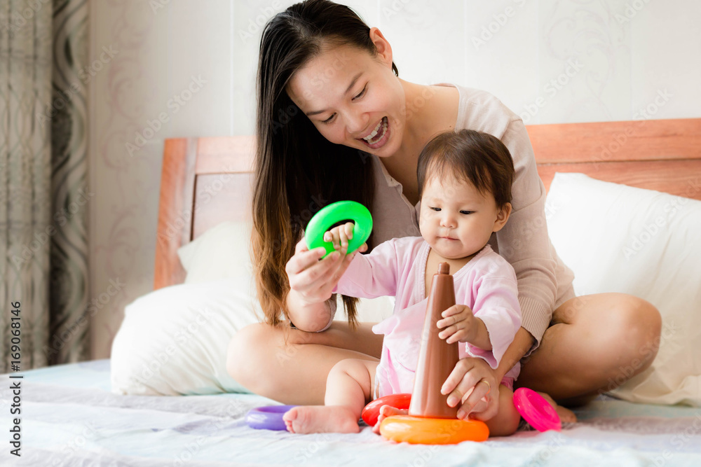 Happy mother teaches 2 year old daughter coordination skills using plastic hoop toys Happy mother teaches 2 year old daughter coordination skills using plastic hoop toys