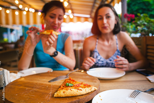 Two girls are eating pizza.