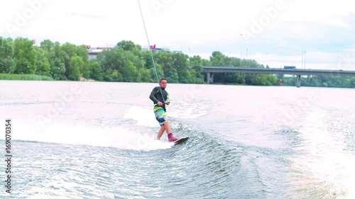 Wakeboarder doing tricks HD wakeboarding slow-motion pov video. Man rides behind boat and jumps somersault flip on waves. Water extreme sport.