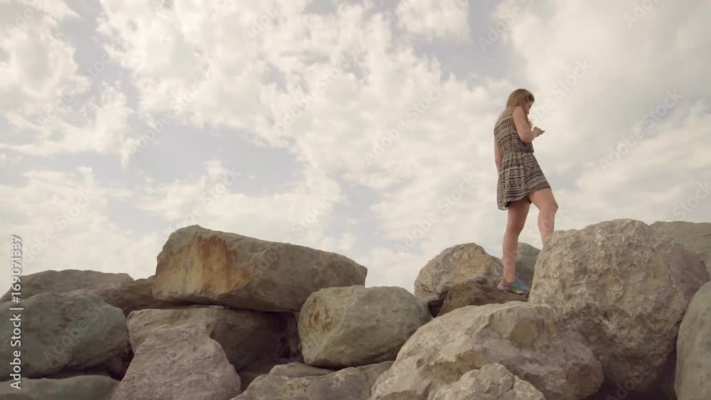 The girl walks on top of the mountain, balancing on a narrow crest, holding a mobile phone in her hand Slow motion The girl walks on top of the mountain, balancing on a narrow crest, holding a mobile phone in her hand Slow motion