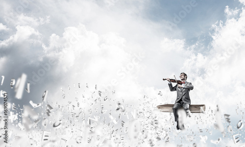 Handsome violinist play his melody and symbols fly around in air