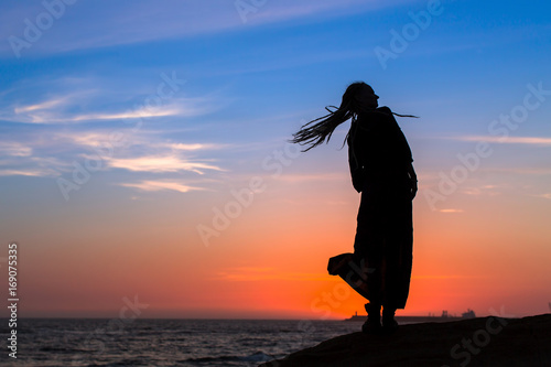 Silhouette woman on the sea beach at amazing sunset.