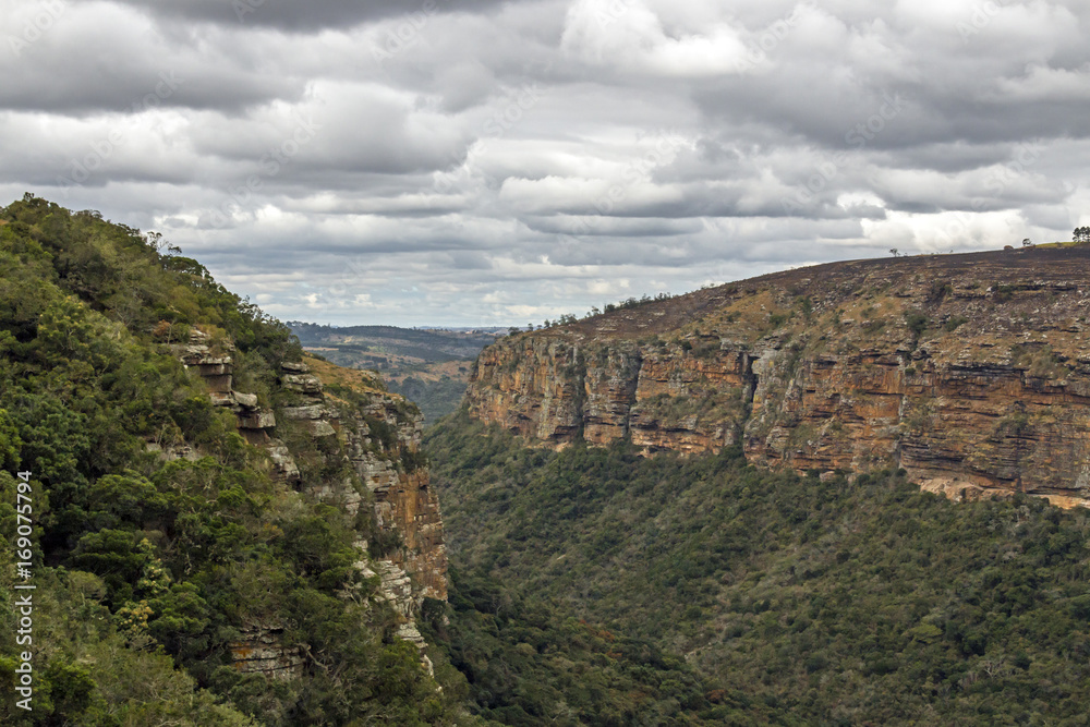 Obraz premium Dry Grassland Gorge Mountains and Valleys Against Cloudy Sky
