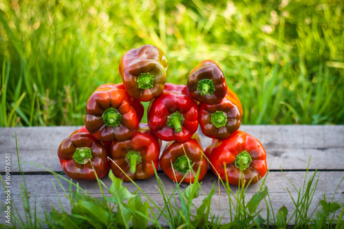 Red pepper lie on a wooden board. Background from a green grass photo