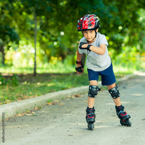 Little boy riding on rollers in the summer in the Park. Happy child in helmet learning to skate. © alexeytsurkan