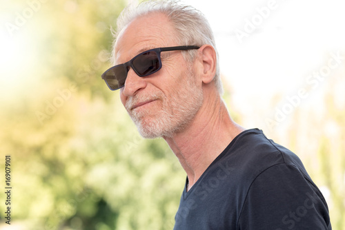 Mature bearded man wearing sunglasses, light effect