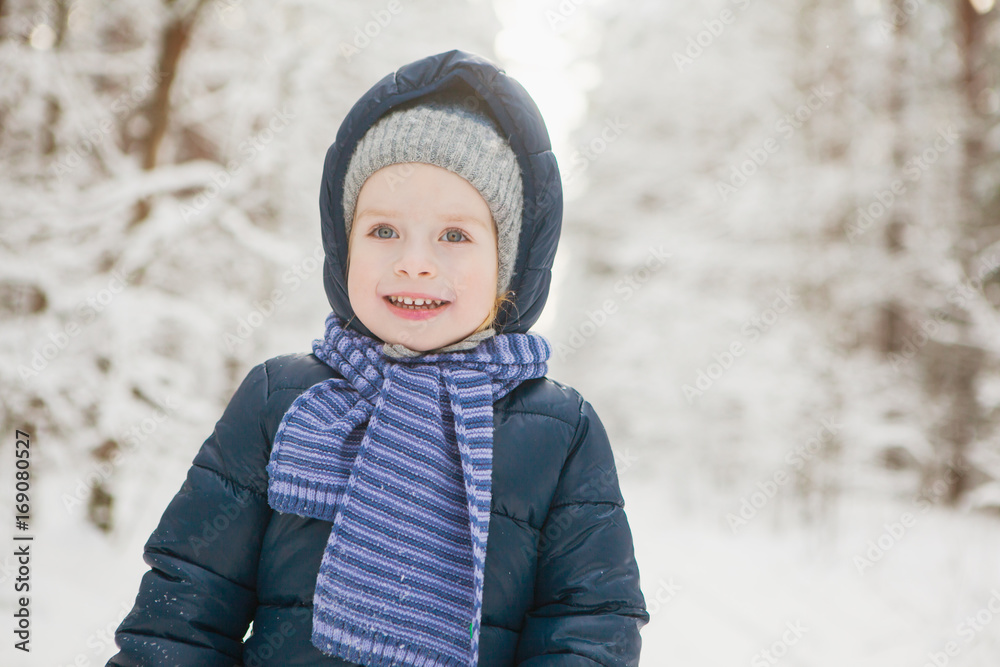 Closeup portrait of little smiling girl in snowy winter forest