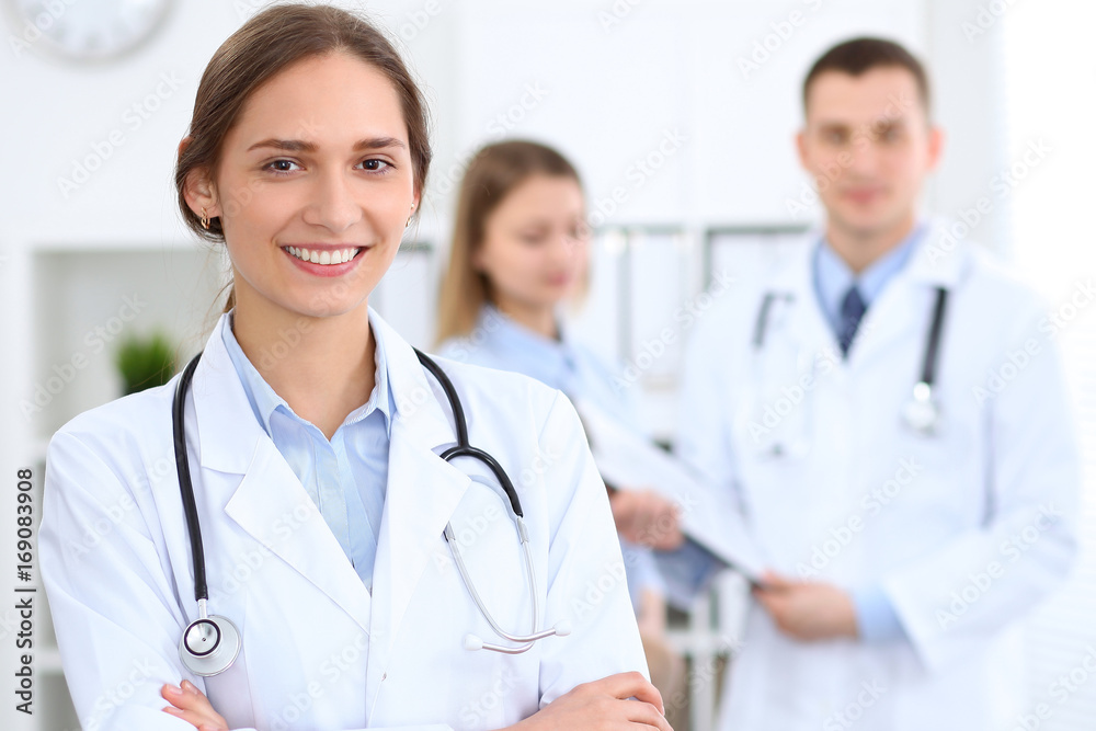 Young beautiful female doctor smiling on the background with patient in hospital Young beautiful female doctor smiling on the background with patient in hospital
