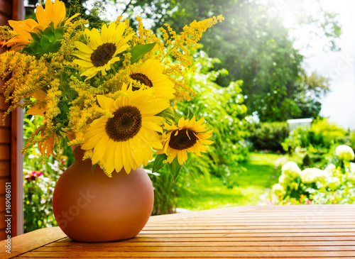 Fototapeta Naklejka Na Ścianę i Meble -  Sonnenblumen und Goldrute auf dem Gartentisch